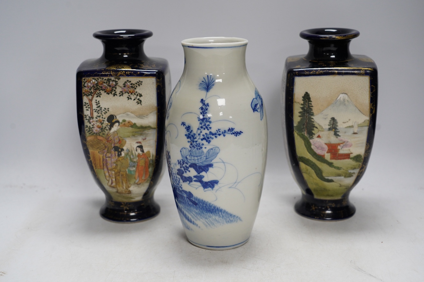 A pair of Japanese satsuma pottery vases and a blue and white Meiji Arita vase, largest 24cm high. Condition - fair